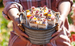A galvinized bucket full of soap bouquets being held by Natalie in the morning sunlight. One soap bouquet will be in each gift set.